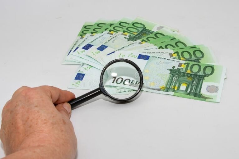 main tenant une loupe sur un billet